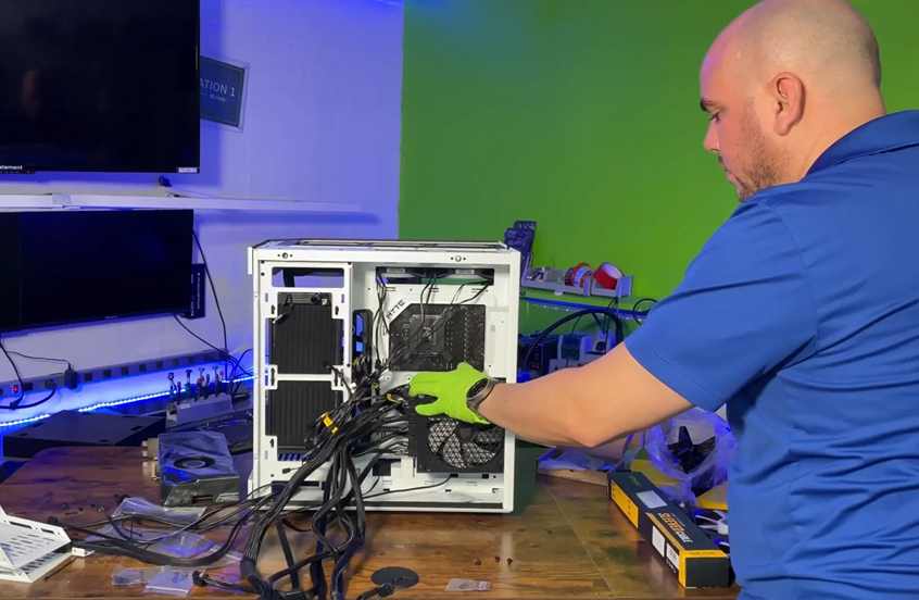 Technician from Prime Tech Support Miami, Florida, expertly installing a power supply unit (PSU) into a gaming PC build.