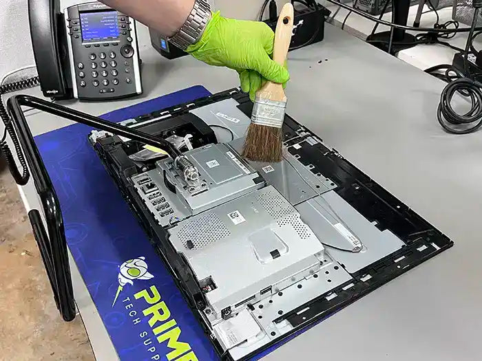 In our Miami-based Prime Tech Support Lab, a technician provides an All-in-One computer cleaning service. They use a brush to remove dust and prevent overheating, ensuring optimal performance of the unit.