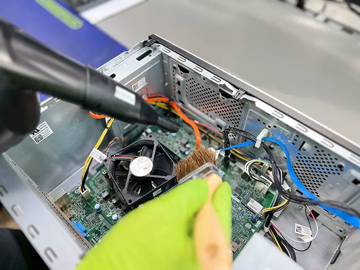 In our Miami lab, a technician utilizes an air cleaning tool and a brush to thoroughly clean and maintain a desktop computer for a customer.