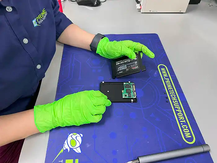 At Prime Tech Support's lab in Miami, a technician performs a desktop data recovery service for a customer. Using a screwdriver, they carefully disassemble the hard drive to retrieve the data.