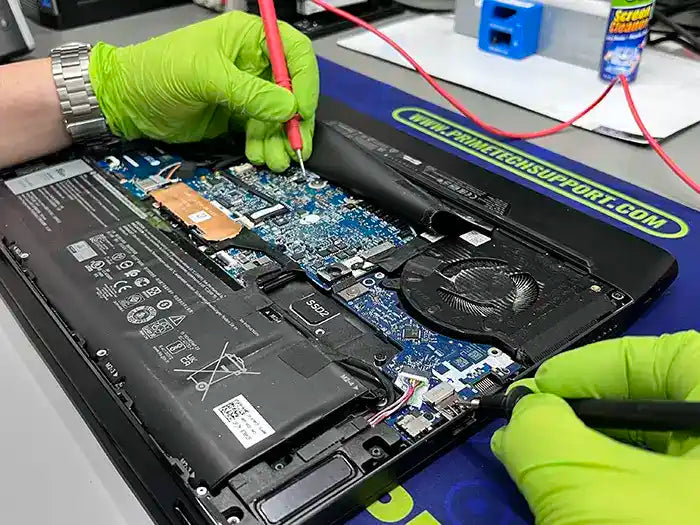 In Miami, a Prime Tech Support technician utilizes a voltage tester to diagnose and repair a gaming laptop for a customer who is a gamer.