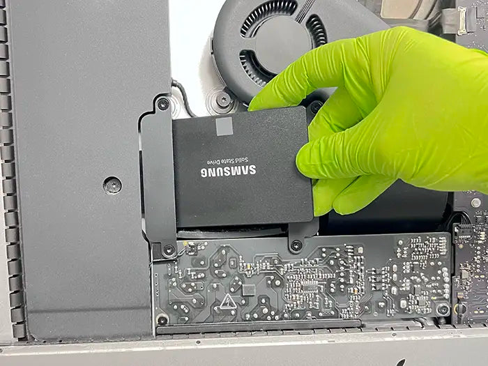 Prime Tech Support technician wearing green gloves and upgrading the memory of an iMac for a client in Miami