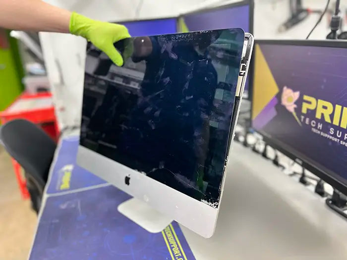 At Prime Tech Support's Miami lab, a technician examines an iMac computer for a customer and proceeds to perform a screen repair service.