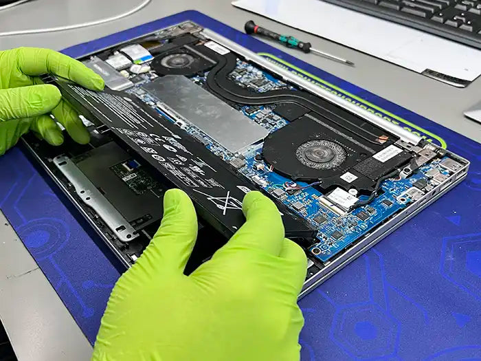 Prime Tech Support technician holding a laptop battery to replace it for a customer in our lab located in Miami Dade County.
