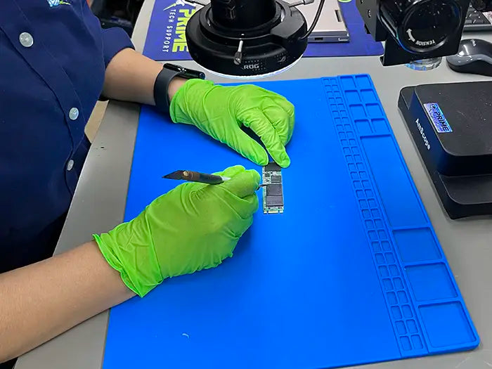 Technician performing a data recovery service for a client located in Miami. He's working with a microscope to take a closer look at the memory damage, repair it and recover the data in the laptop