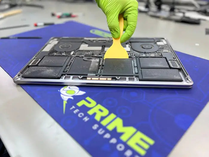 Prime Tech Support Technician using a spatula to carefully remove and replace a MacBook Pro battery in our lab in Miami