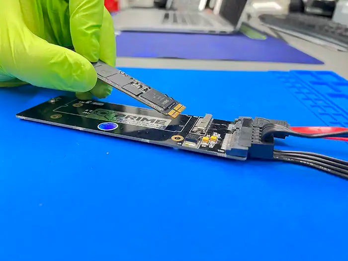 Technician wearing green gloves performing a data recovery service for a MacBook Pro using ultra modern equipment in Prime Tech Support specialized lab