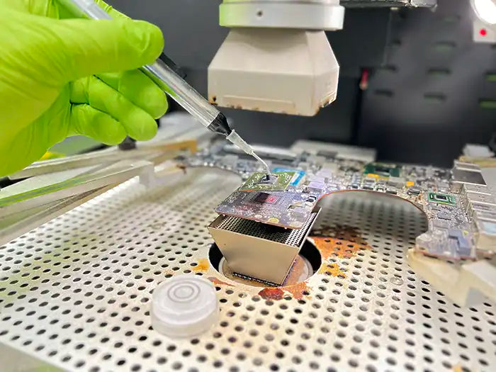 Prime Tech Support technician performing a MacBook Pro Video repair service in our modern lab located in Miami, FL. The technician is using a microscope to examine all the possible damage with the unit and repair it using micro soldering if necessary.