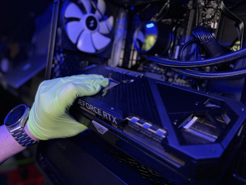 Close-up of Prime Tech Support technician's hand installing an RTX GPU in a gaming PC in Miami, FL
