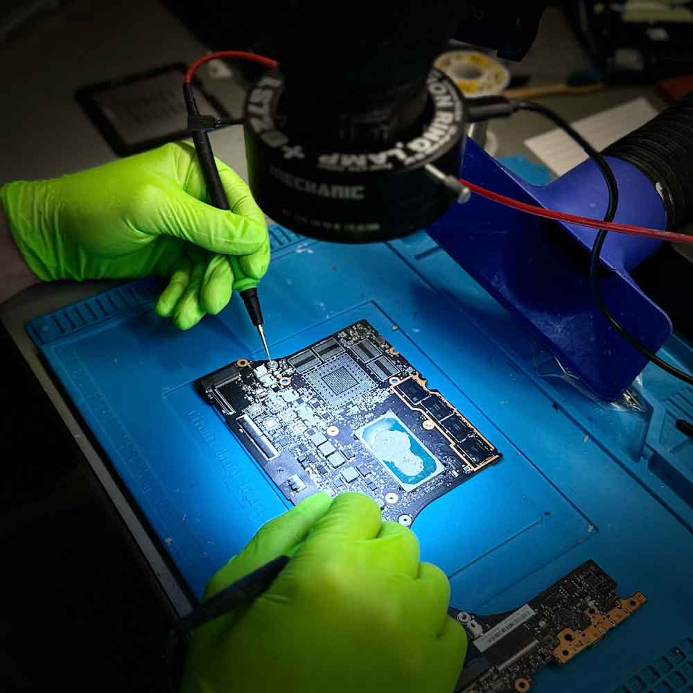 Technician performing MacBook Pro logic board data recovery using microsoldering tools in a professional data recovery lab.