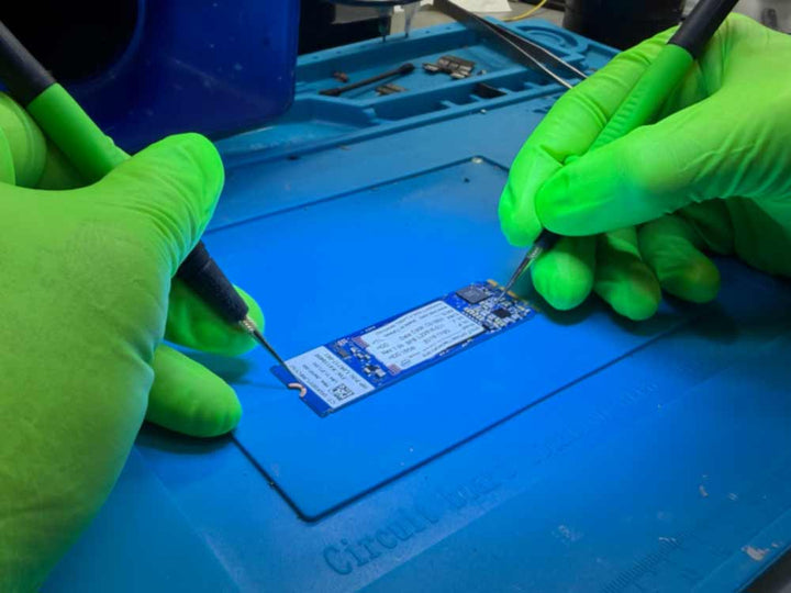 NVMe data recovery work showing a technician handling an NVMe SSD circuit board using precision tools in a lab environment.