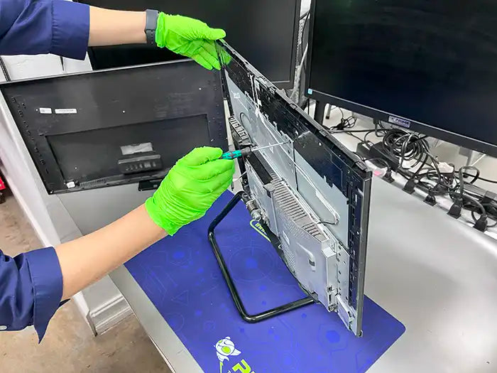 A Prime Tech Support technician disassembles the rear part of an All-in-One computer to conduct a thorough diagnostic and identify any issues with the device.