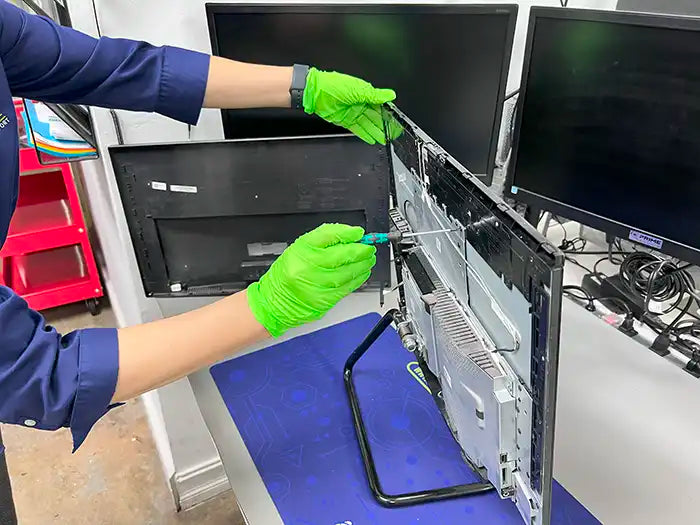 Our computer technician is using a screwdriver to replace the screen of this All-in-One (AIO) computer at our store located in Miami.