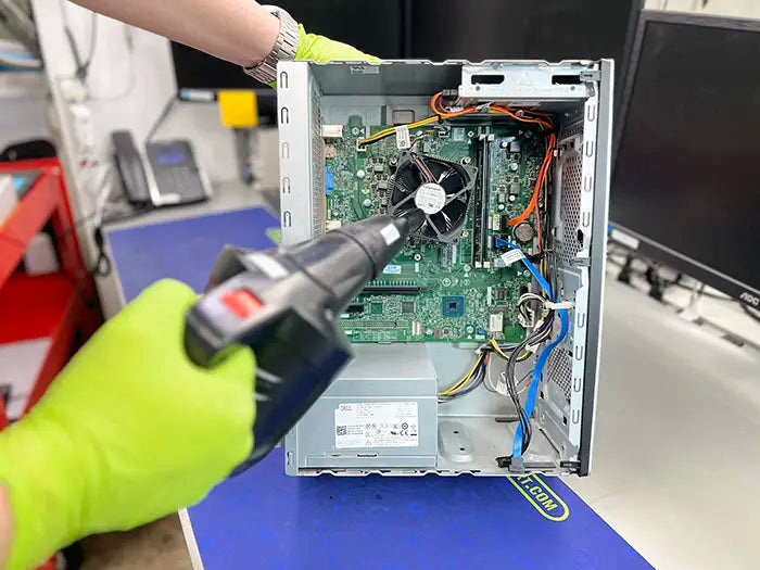 Technician using a air cleaning to perform a deep cleaning and maintenance for a desktop computer in our lab in Miami