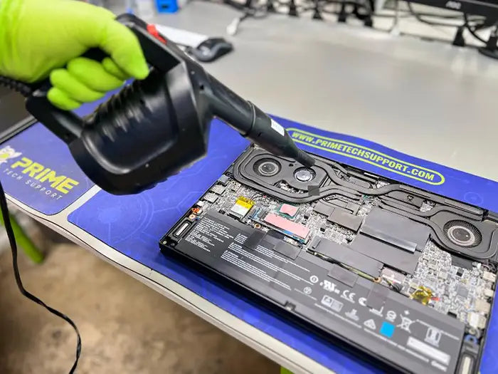 technician using air cleaning tool to deeply clean the fans and all the internal components of the gaming laptop