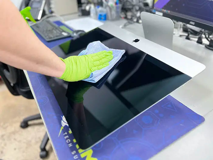 Prime Tech Support technician using a blue cloth to clean the screen of an iMac in Prime Tech Support lab located in Miami