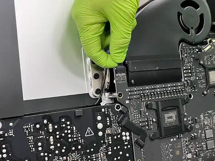 At Prime Tech Support's specialized lab in Miami, a technician is repairing the logic board of an iMac for an Apple client.