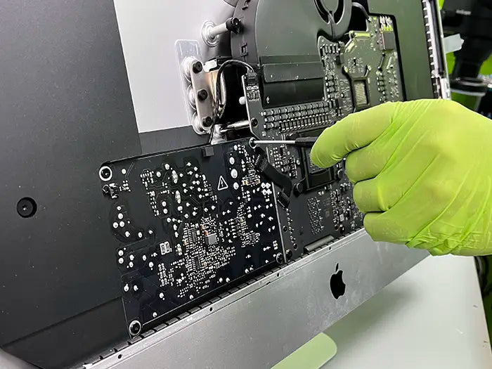Prime Tech Support technician using a screwdriver to dissemble the iMac computer to check and repair the power supply.