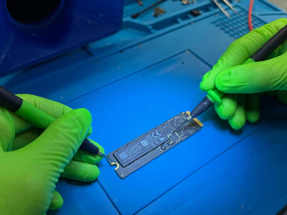 Technician performing component-level data recovery on an iMac SSD in a Miami data recovery lab.