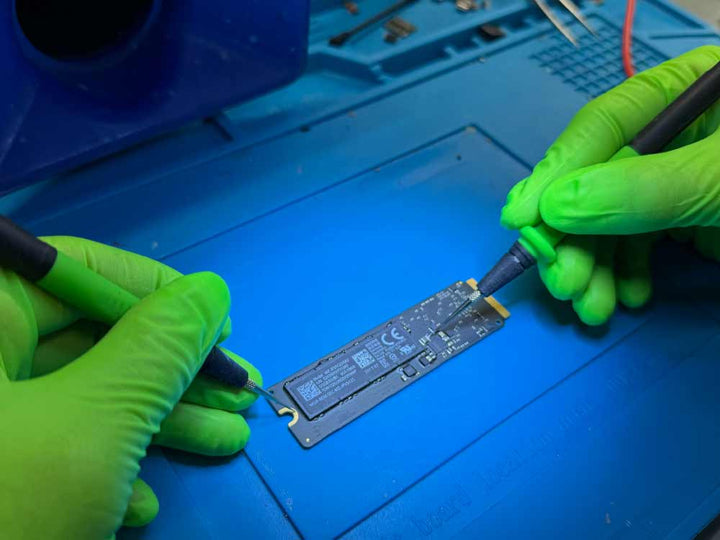 Technician performing component-level data recovery on an iMac SSD in a Miami data recovery lab.
