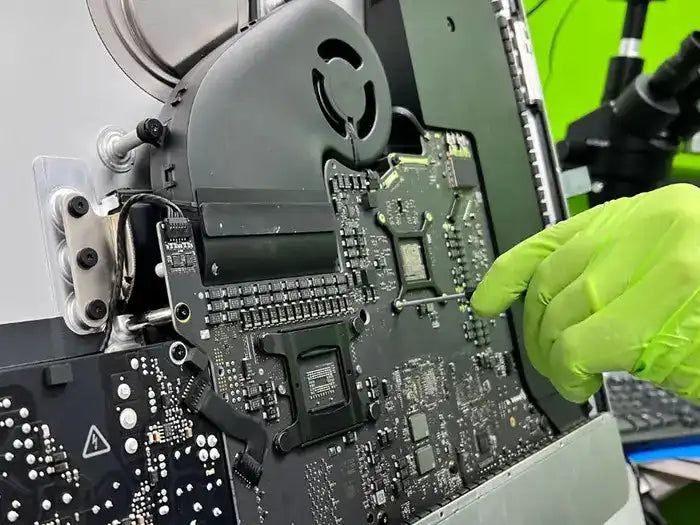 Technician using a screwdriver to dissemble the iMac after diagnosing the Video issue the customer reported at our lab located in Miami