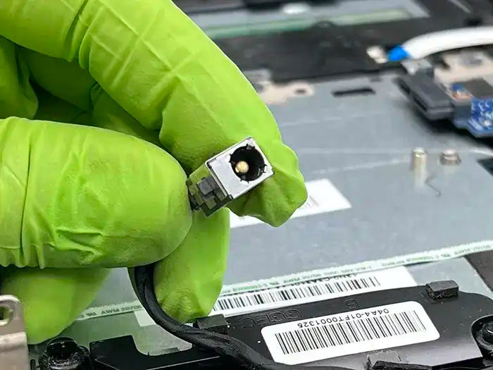 In Miami, a technician is performing a DC jack repair service for a client. The technician inspects the laptop's DC jack port in our specialized lab to identify and fix the issue.