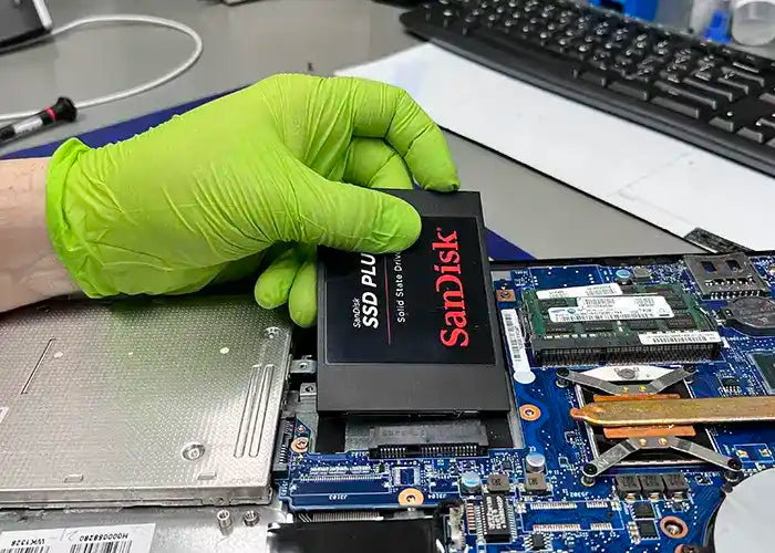 Prime Tech Support technician holding a solid state hard drive to upgrade the memory of a laptop for a client located in Miami Dade County