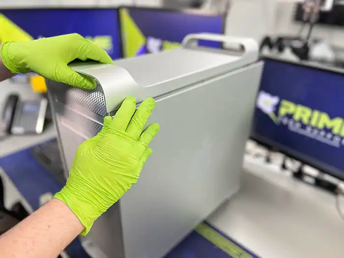 Prime Tech Support technician wearing green gloves and dissembling the case of a Mac Pro computer to examine it and find the cause of the problems in Miami Lab