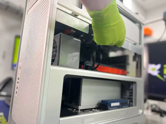 Prime Tech Support Technician wearing green gloves and performing a hard drive replacement in Miami specialized lab for a Mac Pro