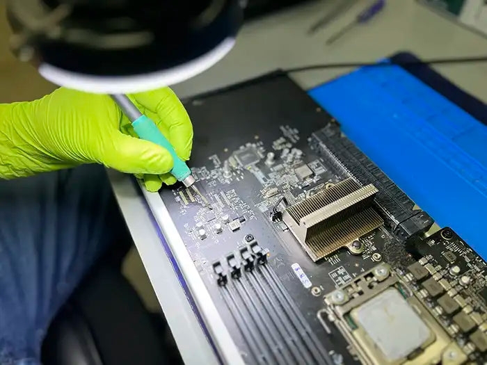 Mac Pro Logic board being inspected and repaired using a microscope by Prime Tech Support technician in our specialized lab located in Miami. He is testing the logic board and examining it to find the issues with it and proceed to repair it.
