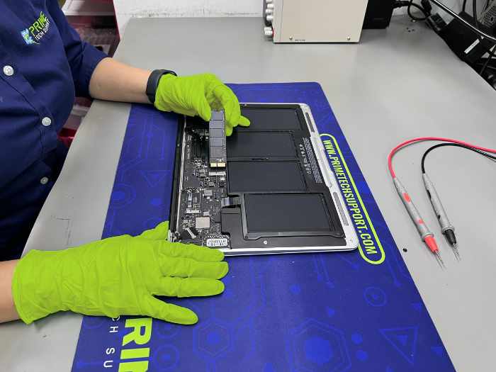 At Prime Tech Support's specialized lab in Miami, a technician wearing green gloves expertly carries out a hard drive replacement for a MacBook Air.