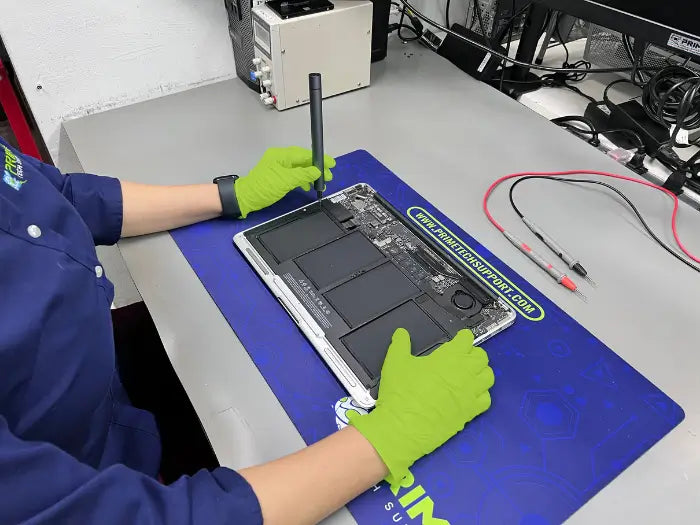 Prime tech Support Technician dissembles the rear part of a MacBook Pro to perform a detailed diagnostic and find the issues with the device.