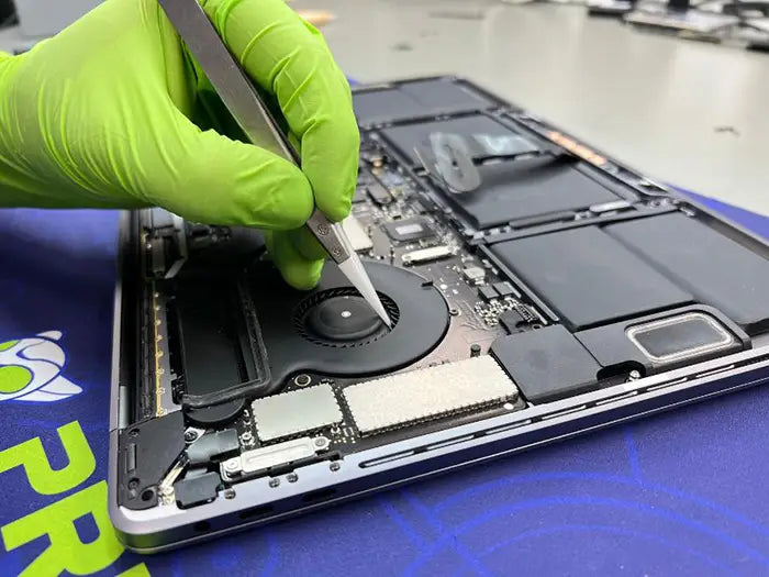 Prime Tech Support technician performing a MacBook Pro diagnostic using some tweezers to examine and inspect all the aspect of the MacBook Pro. This to find the issues and accurately repair them.