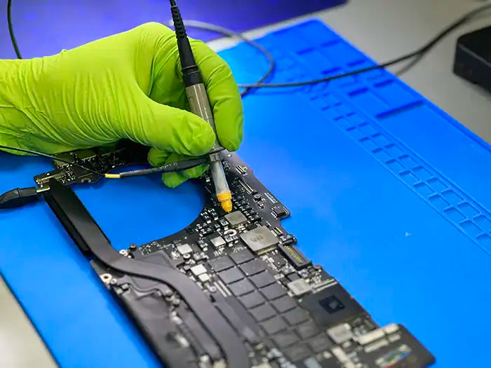 Inside Prime Tech Support's specialized Miami lab, a technician diligently inspects and fixes a logic board. They thoroughly test and examine the board to detect any problems and carry out the required repairs.