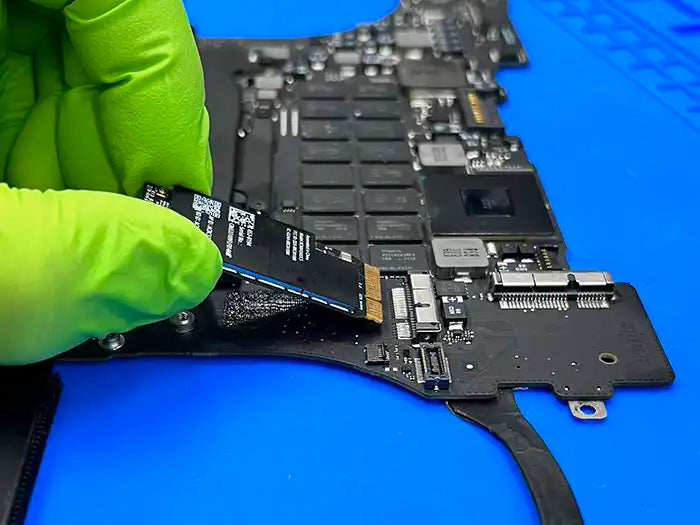Prime Tech Support technician wearing green gloves and extracting a WIFI card from a MacBook Pro to inspect it and repair it.