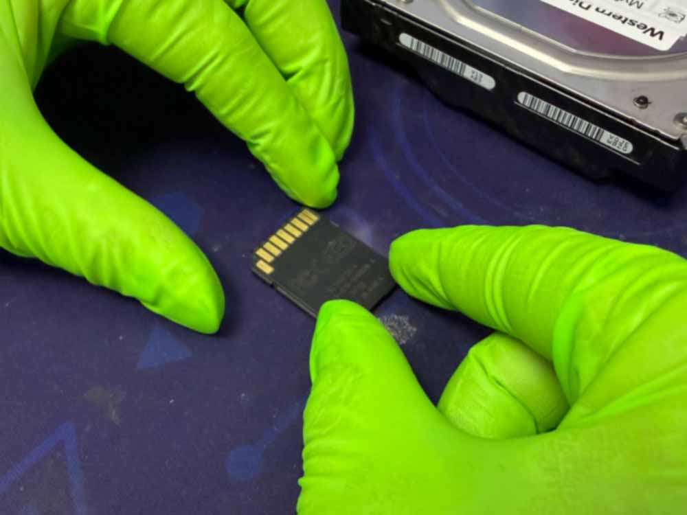 SD card data recovery process showing a technician handling an SD memory card in a professional data recovery lab.