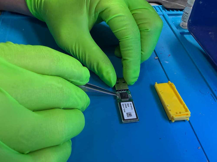 USB flash drive data recovery work showing a technician handling a USB circuit board using precision tools in a lab environment.