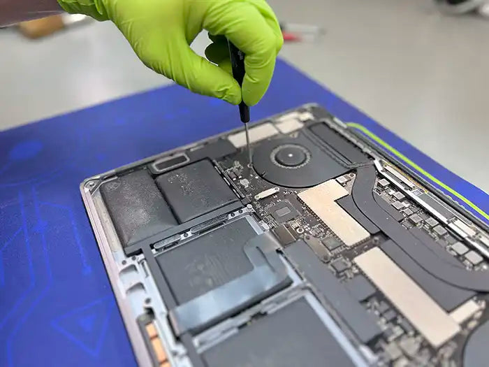 Prime Tech Support technician using a screwdriver to dissemble a MacBook Pro to diagnose it in our Lab